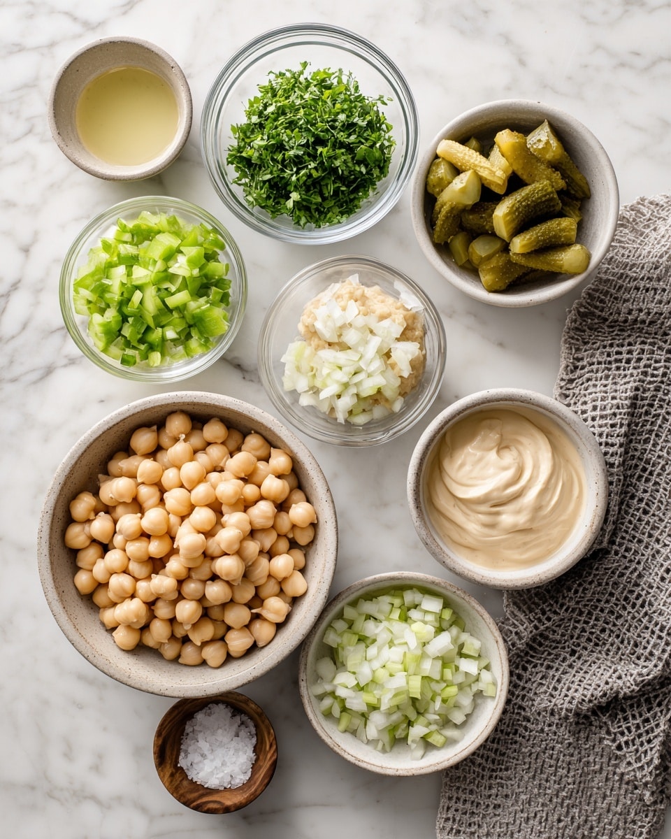 The image shows nine bowls arranged neatly on a white marbled surface, each containing different ingredients. The largest bowl is at the bottom with light beige chickpeas, smooth and round. Above it, small glass bowl holds finely chopped green herbs with a soft, leafy texture. To the right, a white bowl holds small, unevenly cut green pickles. In the center is a small white bowl with a dollop of light brown mustard. To the right, a rustic beige bowl contains smooth off-white mayonnaise. Above it, another beige bowl holds finely chopped white onions with a slightly translucent look. To the left is a white bowl with bright green chopped celery, shiny and fresh. Below that is a small beige bowl with a light yellowish clear liquid, likely lemon juice. A small round wooden bowl with white salt sits near the center. A gray textured cloth is partially visible on the right side. photo taken with an iphone --ar 4:5 --v 7