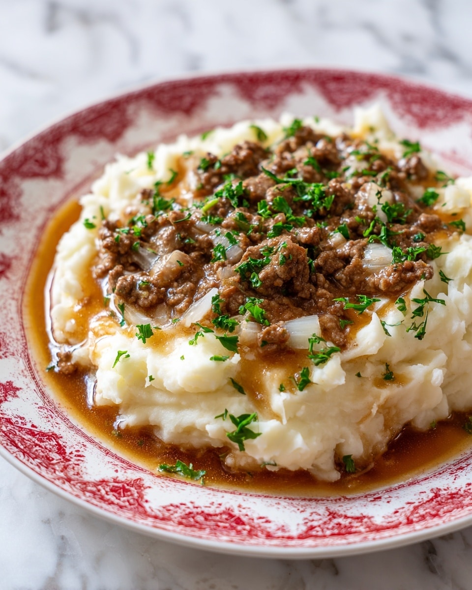 The dish shows two layers on a white plate with a red decorative edge. The bottom layer is a ring of creamy, white mashed potatoes, arranged thickly with a rough, slightly uneven texture. The top layer is a heap of brown ground meat in a shiny, savory sauce with visible bits of onion and small chunks of meat. Green parsley leaves are scattered on top of the meat, adding a splash of color. The plate is set on a white marbled surface. photo taken with an iphone --ar 4:5 --v 7