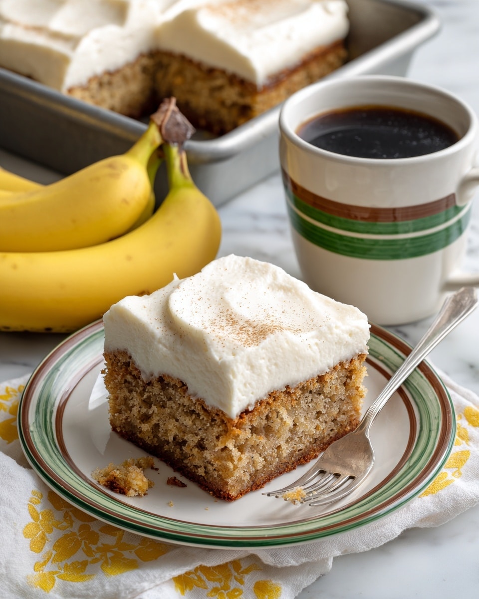 The image shows a square piece of banana cake with two layers: a light brown bottom layer with a moist, crumbly texture and a thick, smooth white cream layer on top. The cake is placed on a white plate with green and brown rings around the edge. A silver fork rests on the plate with a small piece of cake on its tines. Next to the plate, there are two ripe yellow bananas on a white cloth with a yellow pattern. In the background, part of a metal baking pan holds another square piece of the same cake with cream on top. To the right of the plate, there is a white ceramic mug with green and brown bands filled with black coffee. All items are on a white marbled surface. Photo taken with an iphone --ar 4:5 --v 7