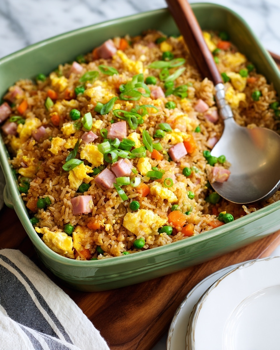 The image shows a close-up of fried rice served on a white plate, topped with small pieces of yellow scrambled eggs, orange carrot cubes, green peas and edamame, and small pink chunks of ham. The rice is mixed with slightly crispy, browned bits giving it a textured look, spread throughout the dish with some clusters on top. A silver fork is placed on the plate with some rice and vegetables resting on its tines. The plate sits on a white marbled surface that adds a clean and bright background to the colorful food photo taken with an iphone --ar 4:5 --v 7