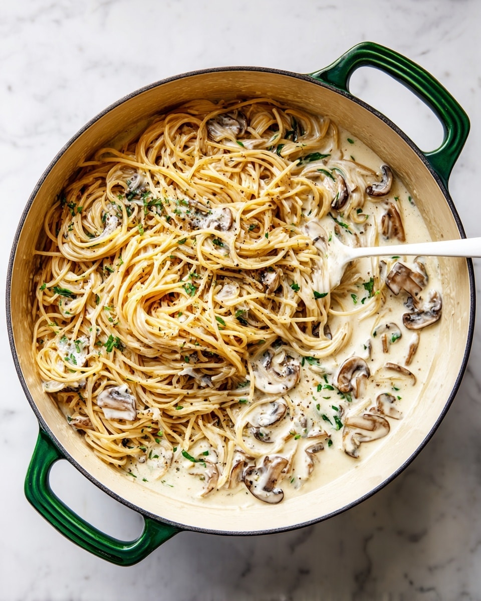 A large white pot with green handles sits on a white marbled surface, filled with a mix of light brown thin spaghetti noodles and creamy white sauce with small chunks of mushrooms. The noodles cover about half of the pot's right side, while the sauce with mushrooms spreads unevenly over the left side. A white spoon rests inside the pot, partly submerged, positioned from the top right towards the center. The creamy sauce has a smooth texture with visible mushroom pieces scattered throughout. photo taken with an iphone --ar 4:5 --v 7