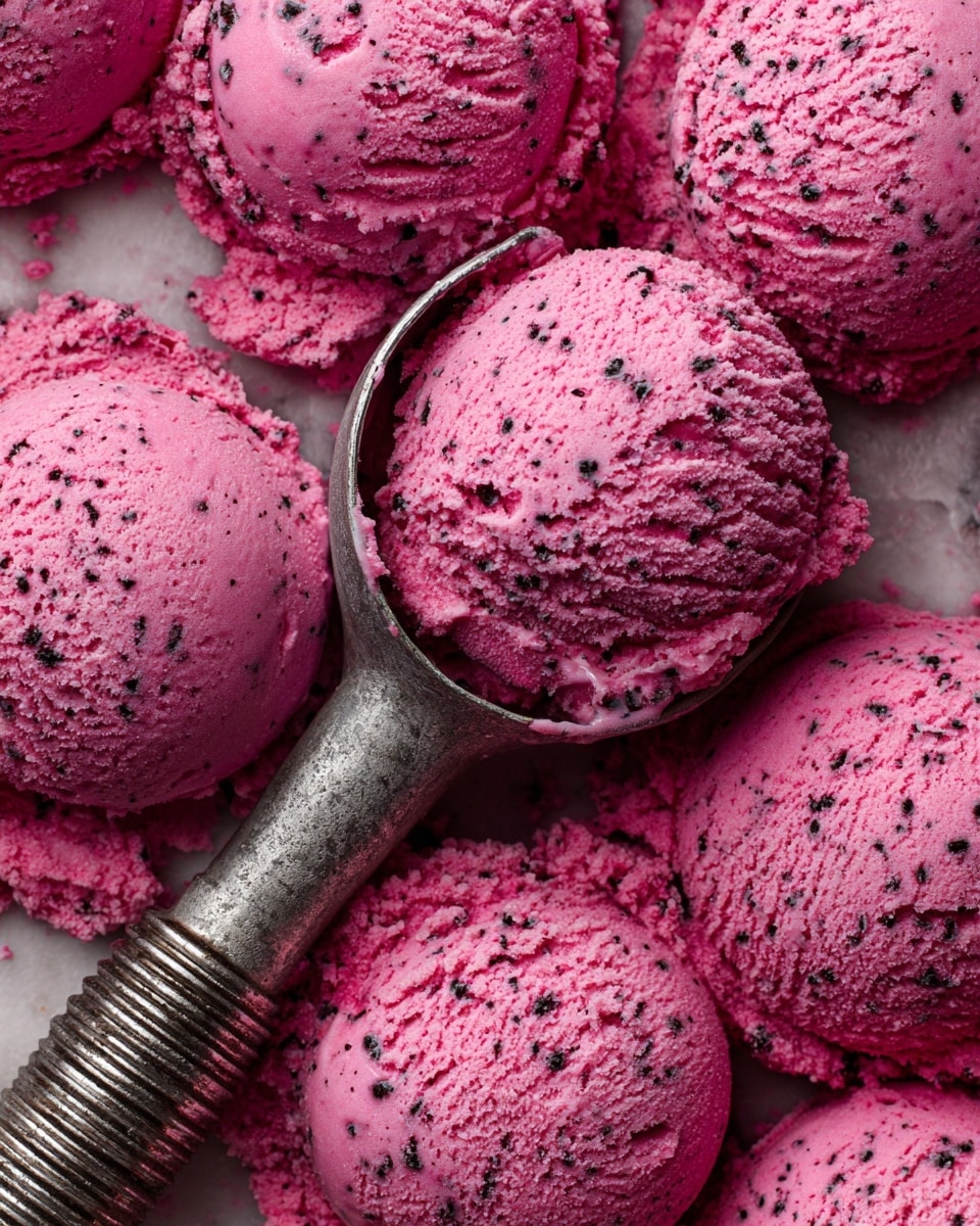The image shows several scoops of bright pink ice cream with a rough, creamy texture filled with tiny dark bits, packed closely together. A metal ice cream scoop with a ridged handle is partly buried in the ice cream, highlighting its dense, slightly crumbly surface. The whole scene is set against a white marbled texture. photo taken with an iphone --ar 4:5 --v 7