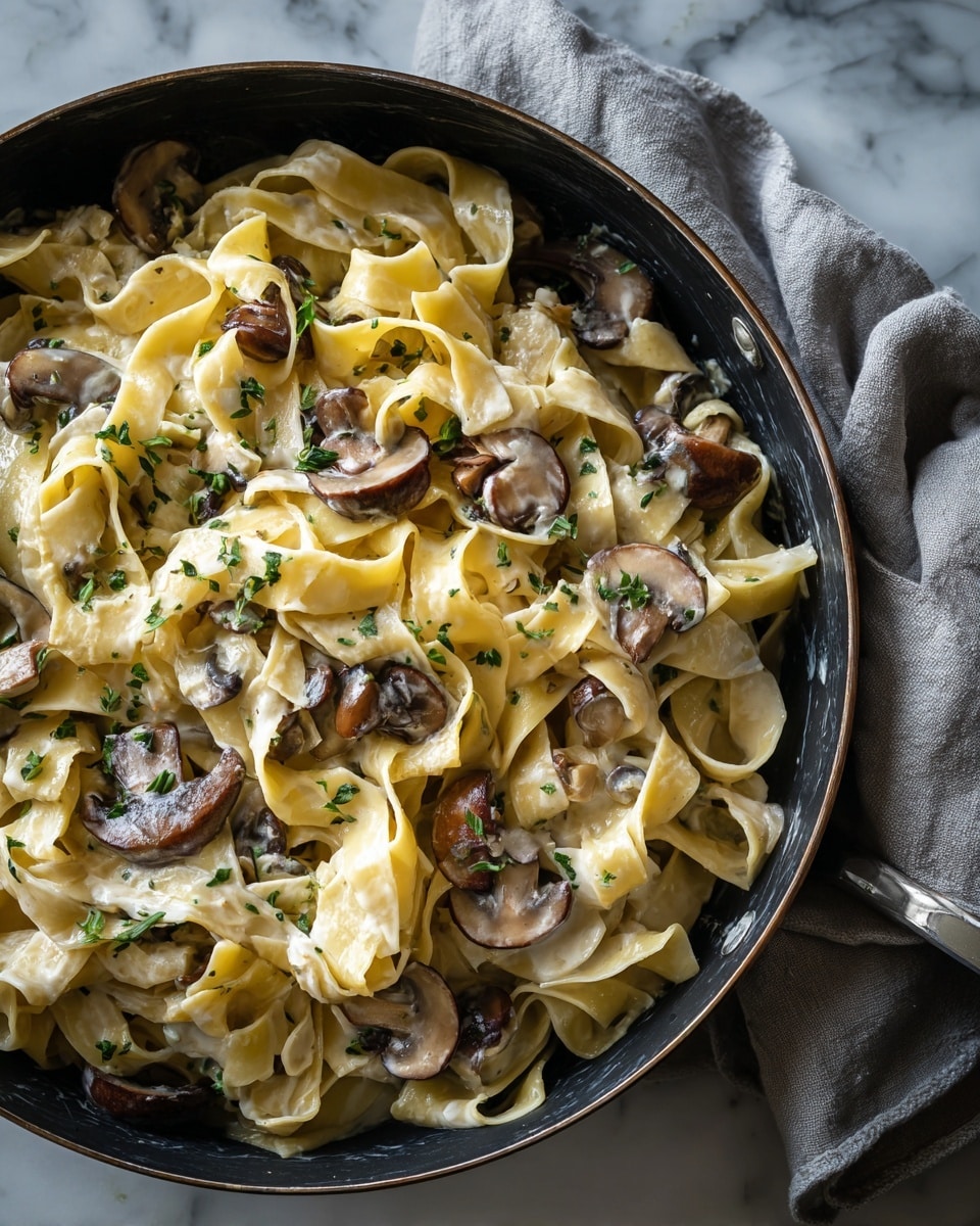 A white plate with a pile of wide, pale yellow pasta noodles at the bottom layer. On top of the pasta, there are several pieces of brown mushrooms with a slightly glossy texture spread out evenly. Shredded white cheese is sprinkled over the mushrooms and pasta, with some small green herb bits mixed in. A silver fork rests on the right side of the plate, touching the pasta. The plate is placed on a white marbled surface with a textured light gray cloth nearby. Part of another white plate filled with similar pasta is visible on the right side. photo taken with an iphone --ar 4:5 --v 7