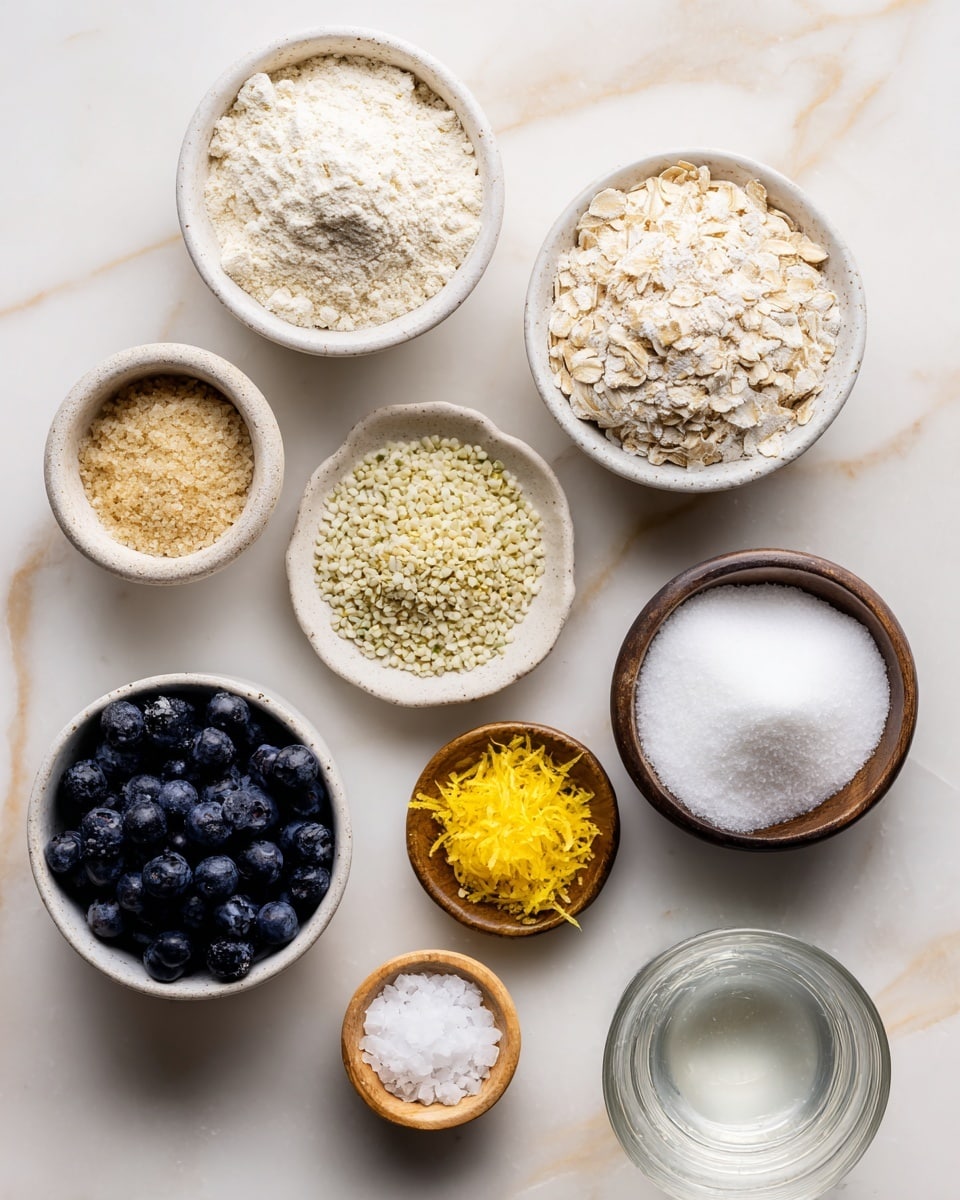 The image shows nine small white bowls on a white marbled surface. The top left bowl contains light beige oat flour with a soft, powdery texture. To its right, the bowl is filled with pale cream oat flakes having a dry, slightly rough texture. Below the oat flour is a bowl with light brown coconut sugar with a crumbly, granular texture. The middle bowl holds small pale yellow-green hemp seeds with a round, pebble-like shape. Next to it on the right, a bowl contains solid white coconut oil with a smooth, creamy texture. At bottom left, a bowl is full of dark blue, round blueberries with a shiny, smooth surface. In the center bottom, there is a bit of bright yellow lemon zest with a fine, shredded texture. To its right, a tiny wooden bowl holds white sea salt crystals. Finally, the bottom right bowl contains white arrowroot or cornstarch powder, fine and soft in texture, next to a glass of clear water. The layout is neat and well lit with soft natural light. Photo taken with an iphone --ar 4:5 --v 7