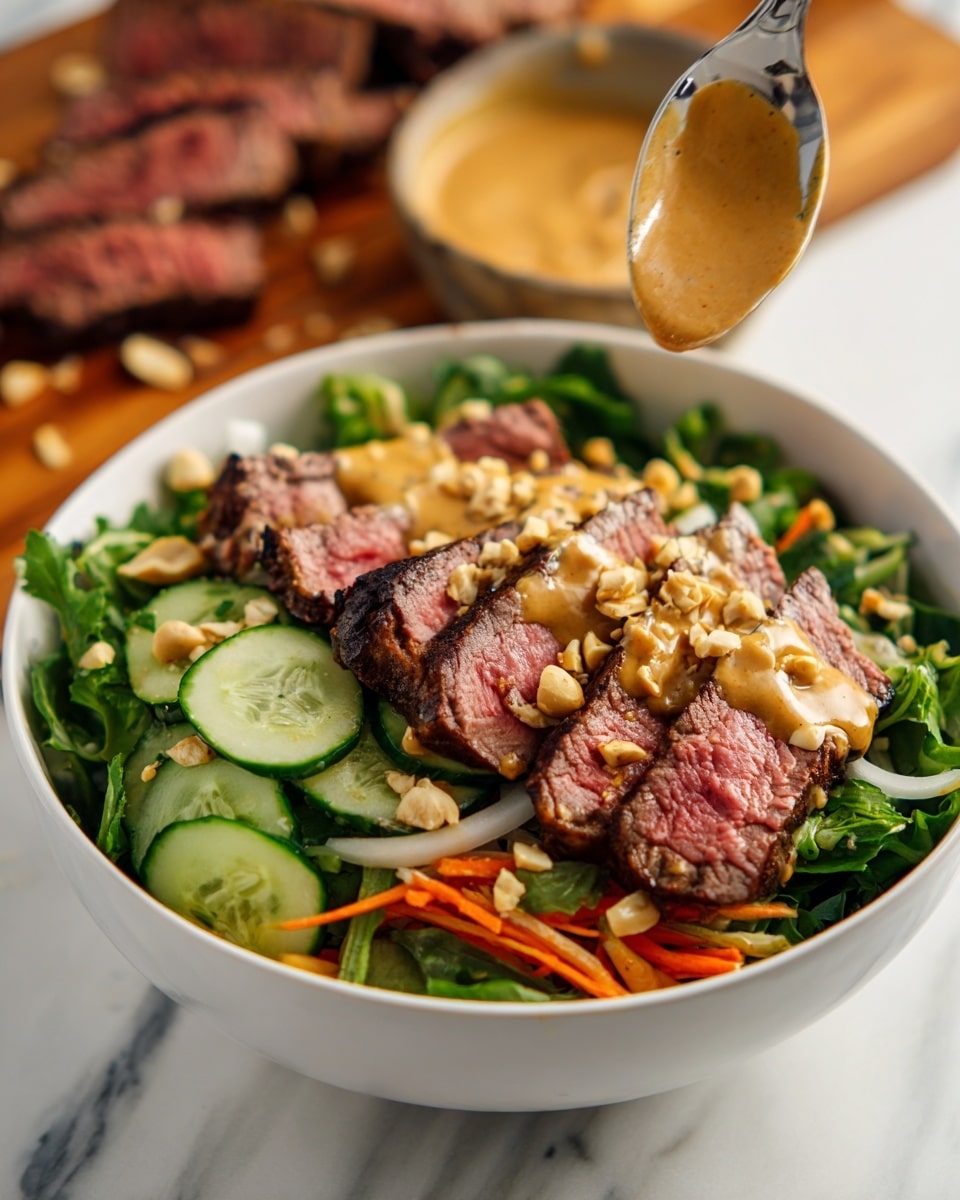 A white bowl filled with a colorful salad layered with bright green leafy herbs and mixed greens at the base, topped with sliced cucumbers showing light green and white colors, thin carrot shreds adding orange brightness, and thin white strips of onion. Centered on top are several slices of medium-rare steak with a pink center and a dark brown sear on the edges. The steak is covered with a thick layer of creamy tan-colored peanut sauce, sprinkled with chopped light beige peanuts. Above the bowl, a metal spoon holds more peanut sauce dripping down onto the salad. In the blurred background, more sliced steak rests on a wooden cutting board against a white marbled surface. photo taken with an iphone --ar 4:5 --v 7