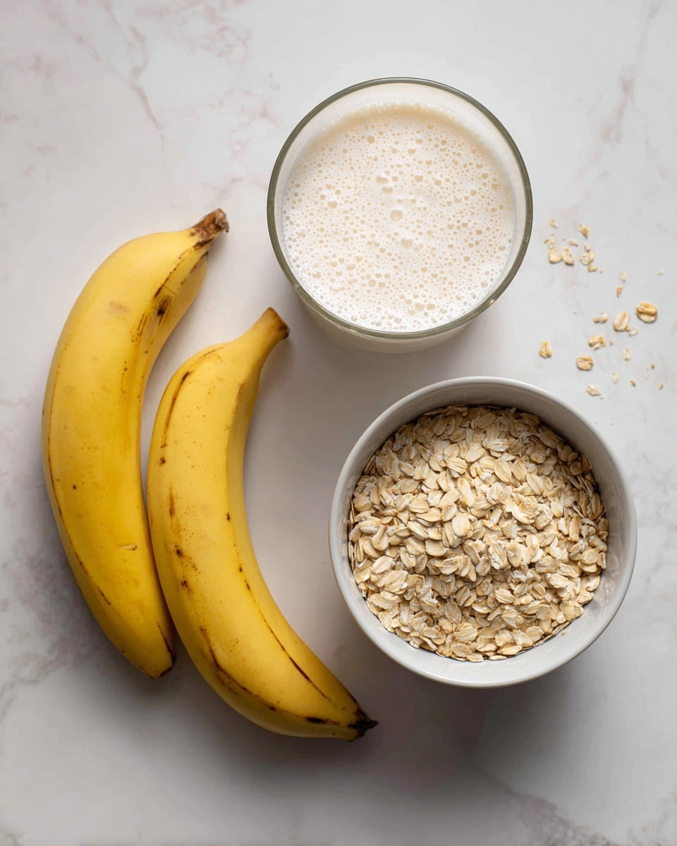 The image shows three main items on a white marbled surface: on the left, two yellow bananas with slight brown spots rest next to each other; in the middle, a clear glass measuring cup filled with creamy, frothy milk with bubbles on top; and on the right, a white bowl filled to the top with light tan rolled oats with some scattered oats around it. The overall colors are soft and natural, and the arrangement is simple and neat. photo taken with an iphone --ar 4:5 --v 7