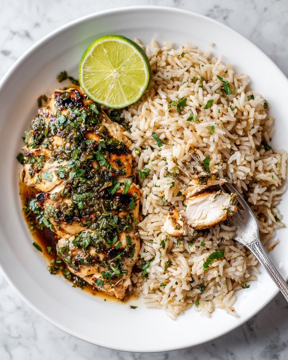 A white round plate on a white marbled surface holds a dish with two main parts: on the left side, a piece of grilled chicken topped with green herbs and a dark sauce, with a lime wedge placed beside it; on the right side, a portion of light brown cooked rice mixed with small green herb bits. A silver fork is lifting a small piece of chicken near the lime, and some rice grains are scattered around the fork. The colors are warm and fresh with green, light brown, and golden-brown tones. photo taken with an iphone --ar 4:5 --v 7
