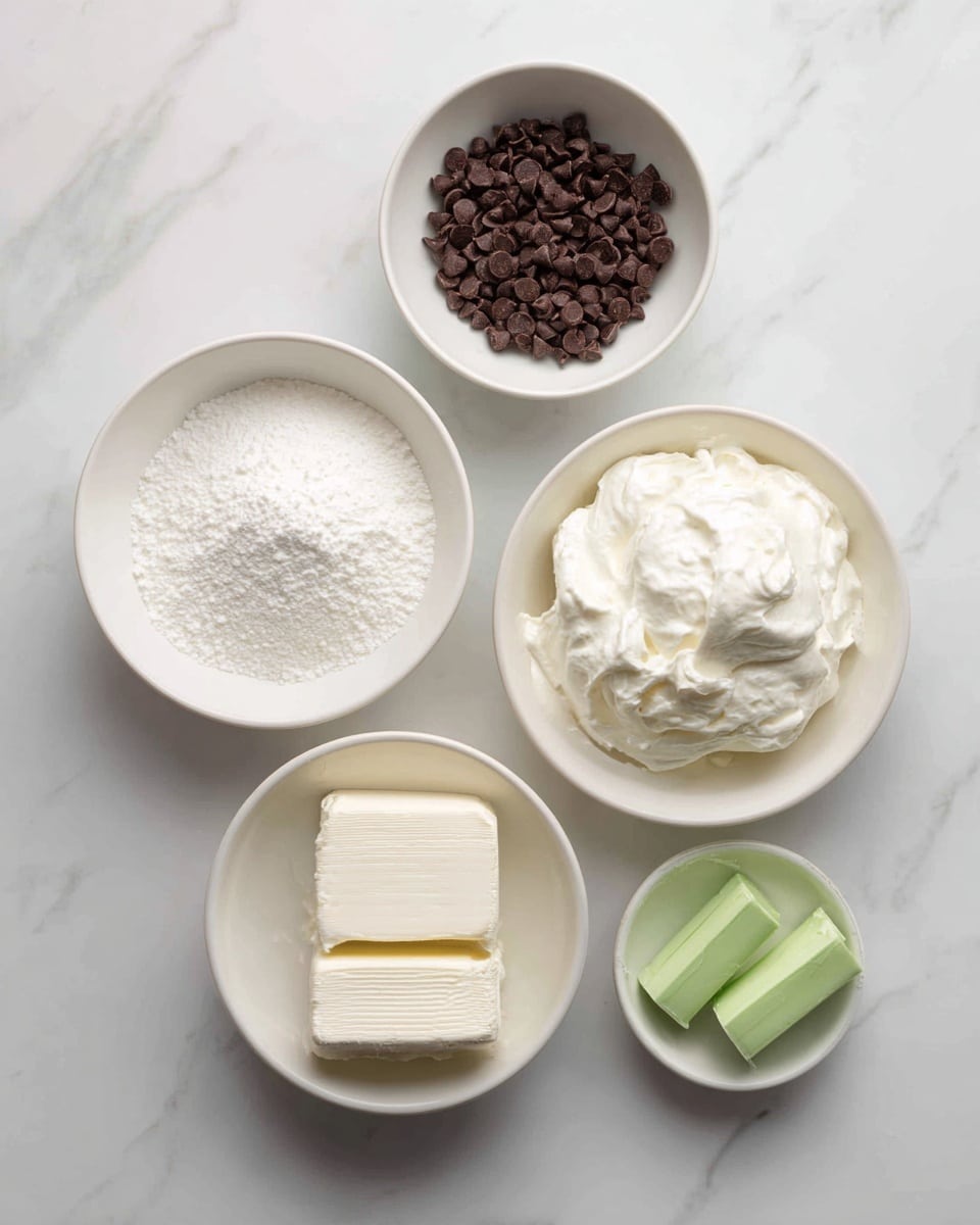 The image shows six round white bowls on a white marbled surface, each containing one ingredient. The top left bowl is filled with small, dark brown chocolate chips, while the top right bowl is empty, labeled for mint extract. Below them, the left bowl holds fine powdered sugar in a soft white color, and the larger bowl next to it contains smooth, fluffy whipped topping, both bright white. At the bottom right, a small green gel food color tube is placed next to a bowl with two blocks of cream cheese, which appear dense and creamy white. The arrangement is clean and simple with clear labels on each bowl, visible from a top-down view. Photo taken with an iphone --ar 4:5 --v 7