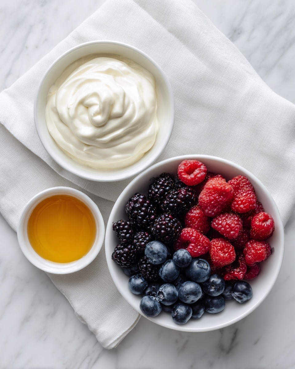 Three white bowls are placed on a white marbled surface with a white cloth underneath. The largest bowl on the right is filled with a mix of fresh berries, including red raspberries, dark blackberries, and blue blueberries, creating a colorful and textured look. To the left of it, there is a medium bowl full of smooth white Greek yogurt, showing soft swirls on its surface. Below these two bowls, a small bowl contains golden honey with a shiny texture. The scene is bright and clean, showing each element clearly. Photo taken with an iphone --ar 4:5 --v 7
