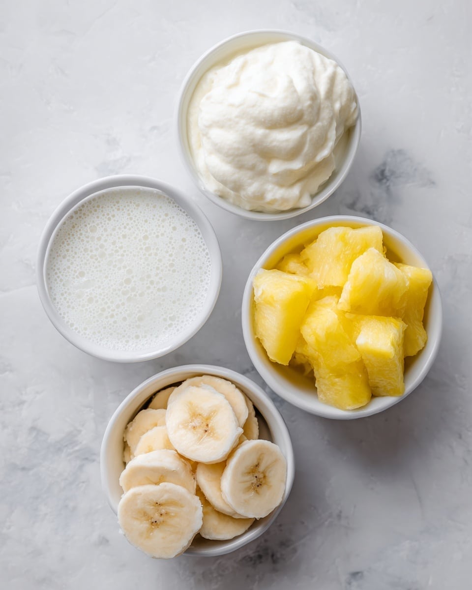 The image shows four small white bowls on a white marbled surface, each containing a different ingredient. The top left bowl holds smooth, white coconut milk with a slightly bubbly texture on top. To the right, another bowl is filled with thick, creamy coconut or Greek yogurt that has a soft, slightly uneven surface. Below on the left, a bowl contains round slices of frozen banana, pale yellow with a frosty coating. On the bottom right, the last bowl holds bright yellow frozen pineapple chunks, with a slightly icy texture. The bowls are evenly spaced and viewed from above. photo taken with an iphone --ar 4:5 --v 7