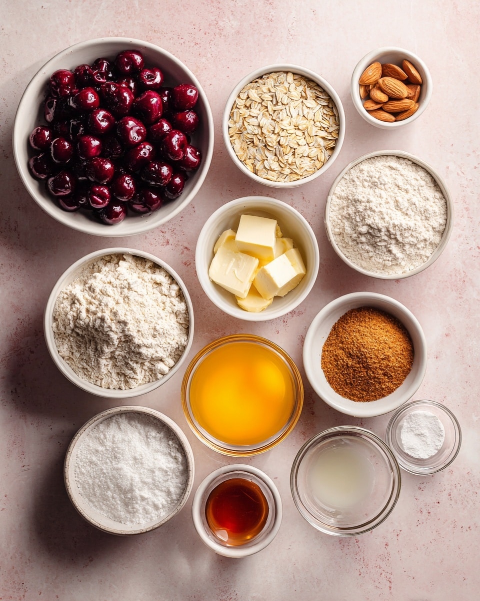 The image shows eleven white bowls and small glass bowls arranged neatly on a soft pink background. The largest bowl is filled with dark red fresh or frozen cherries with a shiny texture. Surrounding it are medium and small white bowls filled with a variety of dry and liquid ingredients: an all-purpose flour bowl with a light, powdery texture, a rolled oats bowl with flat, pale beige flakes, a bright yellow-orange non-dairy butter in a glass bowl, almond flour with a pale beige powdery look, slivered almonds in a bowl with thin, light beige nut pieces, and a brown sugar bowl with a rich, coarse texture. Smaller glass bowls hold lemon juice, vanilla extract, almond extract, baking powder, powdered sugar, and cornstarch, each showing clear or white powdery contents. The whole scene is on a white marbled texture surface with soft natural light photo taken with an iphone --ar 4:5 --v 7