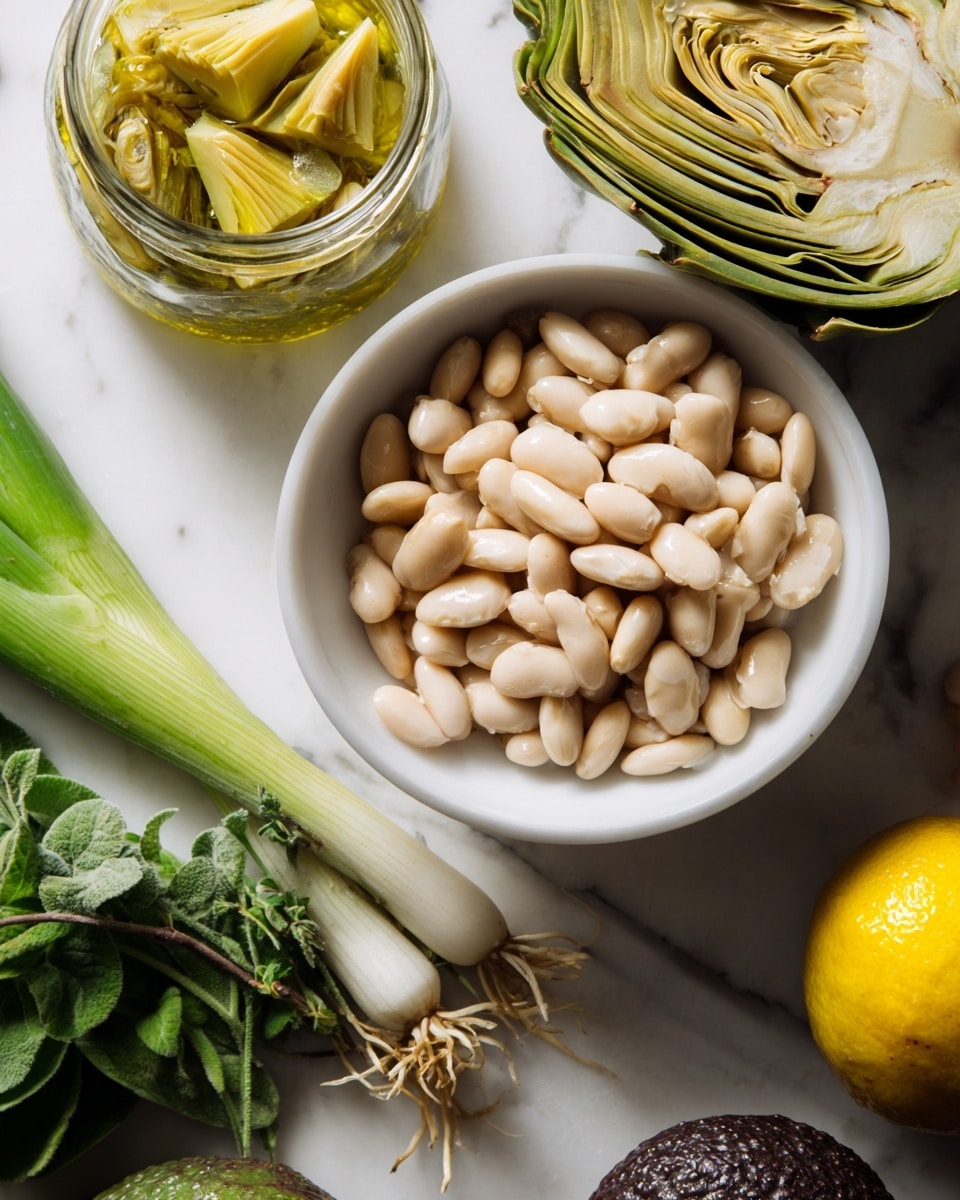 A close-up view of a white bowl filled with light beige beans, resting on a white marbled surface. Next to the bowl on the left is a small open glass jar filled with sliced artichoke hearts in a yellowish oil. Below the jar are fresh green leafy herbs, a whole green chili, and a long green onion with white and light green parts showing. On the right bottom corner, a yellow lemon and a dark brown avocado are partially visible, adding contrast to the image. Photo taken with an iphone --ar 4:5 --v 7