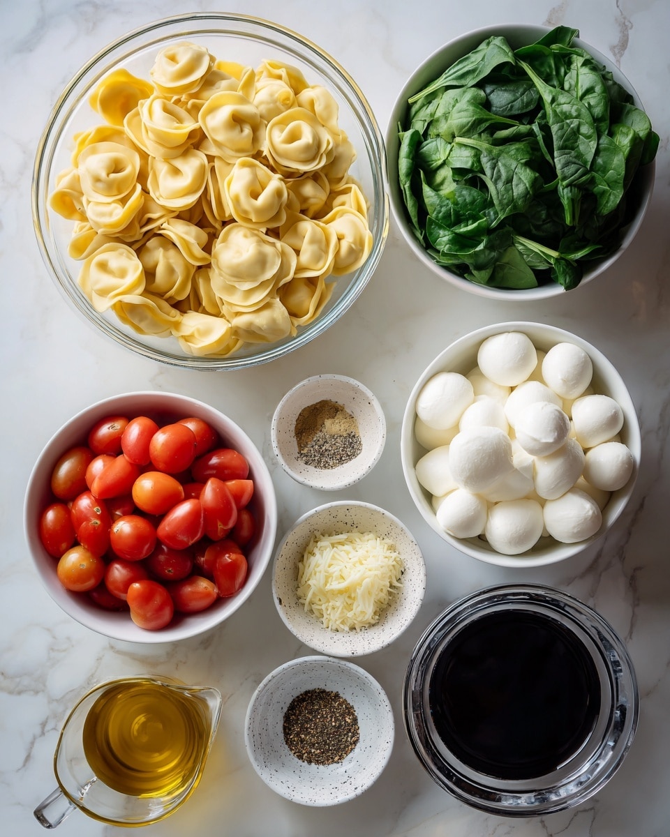 A clear glass bowl filled with pale yellow tortellini is placed on the left side. To the right, there is a white bowl with chopped green spinach at the top and a white speckled small bowl with sliced darker green basil below it. Below these bowls, in the center, a large white bowl holds bright red cherry tomatoes, some halved to show the juicy inside. Next to it, a small white bowl contains minced pale yellow garlic. Below that, a small clear bowl holds black and white salt and pepper mix. Another small clear bowl contains a brownish-green Italian seasoning. At the bottom right corner, a white bowl contains white mozzarella pearls. On the left side, a small white bowl holds dark brown balsamic vinegar. Below it, a clear glass measuring cup holds yellow olive oil. Next to it, a small clear glass pitcher contains thick dark balsamic glaze. The items are arranged on a white marbled surface. Photo taken with an iphone --ar 4:5 --v 7
