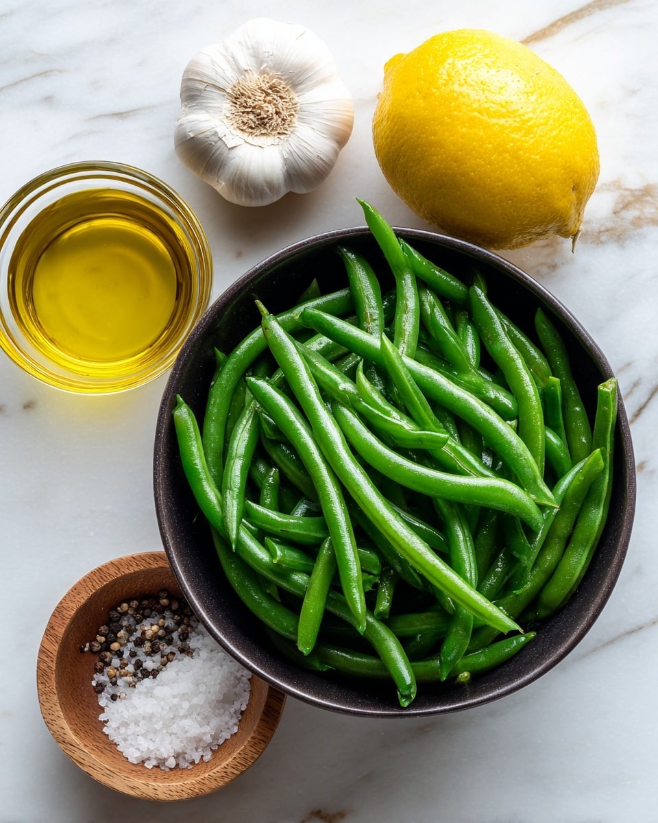 The image shows a dark bowl filled with fresh green beans, placed in the center on a white marbled surface. Above the bowl to the left is a whole garlic bulb, and to the right is a whole lemon next to a small glass container of golden olive oil. Below the bowl, there is an open wooden container filled with coarse salt and pepper. The items are neatly arranged and the background is bright with natural light highlighting the fresh textures. Photo taken with an iphone --ar 4:5 --v 7