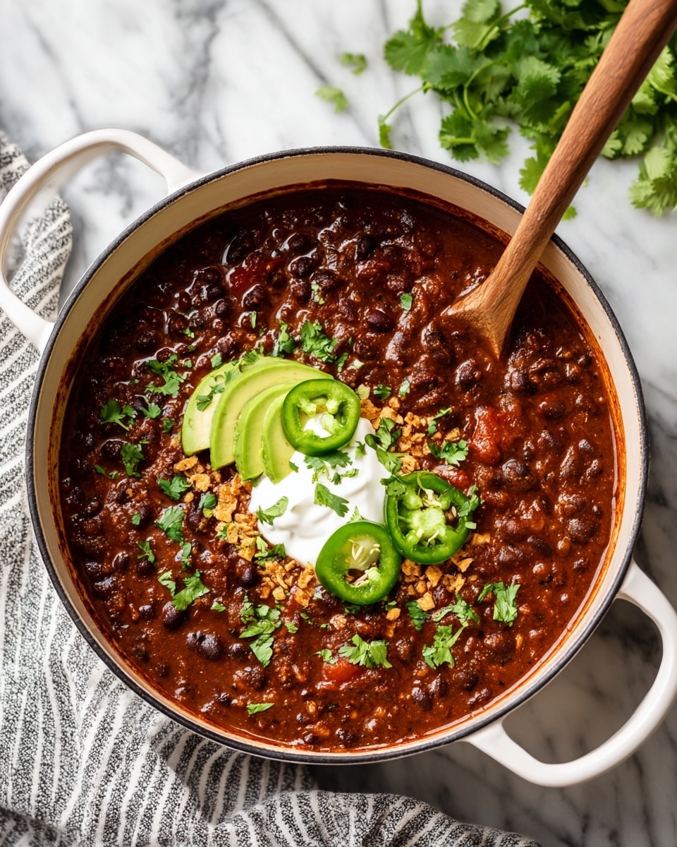 A white bowl filled with thick red chili soup that has black beans and corn kernels mixed inside. On top, there is a layer of crunchy golden tortilla chips scattered unevenly, slices of bright green avocado are placed on one side, and some thin round slices of fresh jalapeño pepper. A big dollop of white sour cream sits in the middle, sprinkled with small pieces of green cilantro. The bowl is placed on a white marbled surface with some extra crushed tortilla chips and cilantro leaves scattered around. A silver spoon is inside the bowl resting on the left side. Photo taken with an iphone --ar 4:5 --v 7