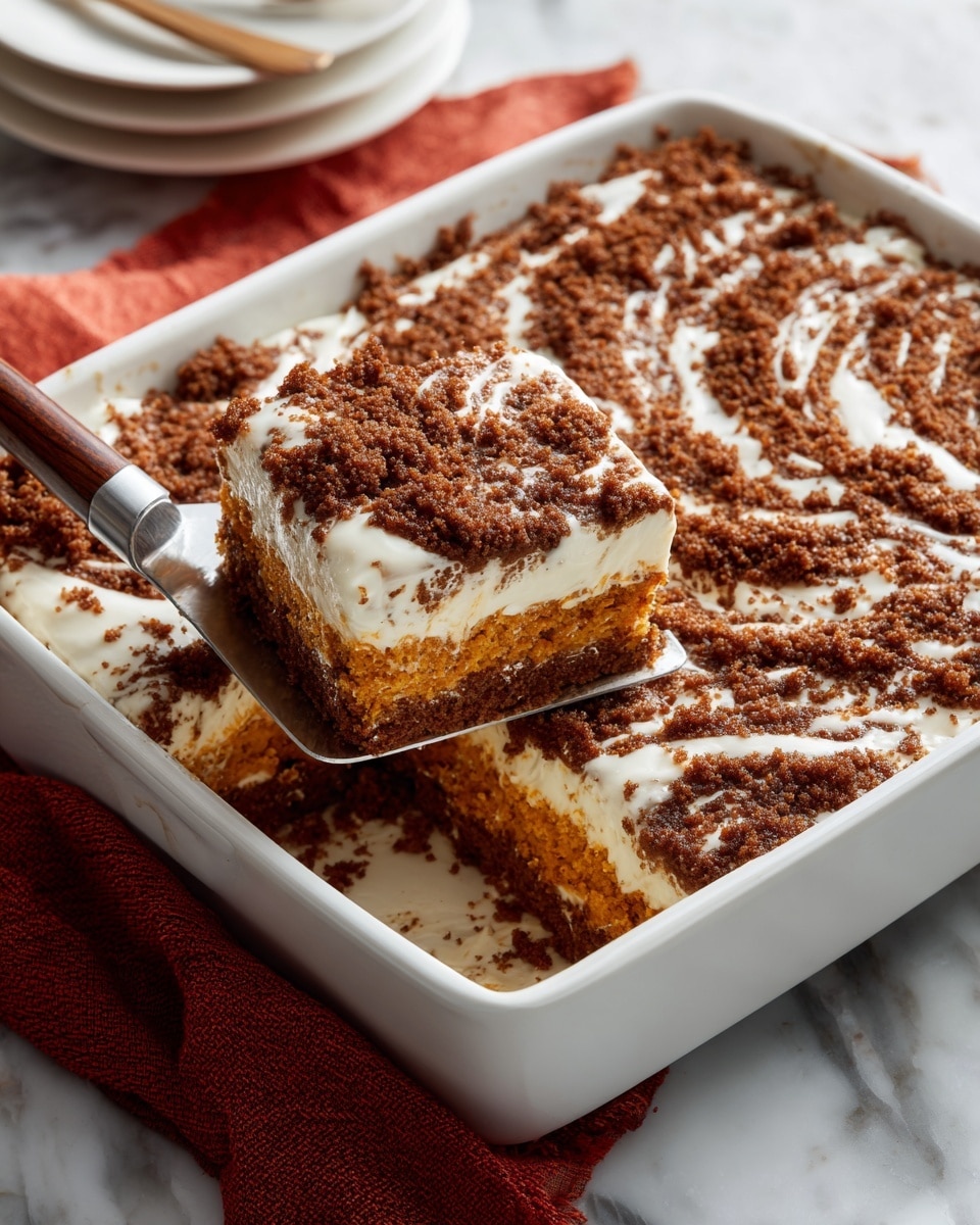 A white rectangular baking dish holds a layered dessert with three visible layers. The bottom layer is a soft, bright orange cake. The middle layer is a dark brown crumbly topping spread thickly, creating a rough texture with swirled patterns. The top layer is a light, white icing drizzled unevenly over the crumb layer, adding a smooth contrast. A metal spatula with a wooden handle lifts one square piece from the dish, showing the layers clearly. The dish is set on a white marbled surface with a folded red cloth nearby. photo taken with an iphone --ar 4:5 --v 7